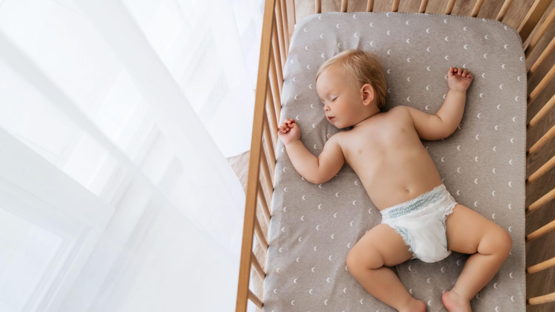 Bambino che dorme in culla con pannolino.