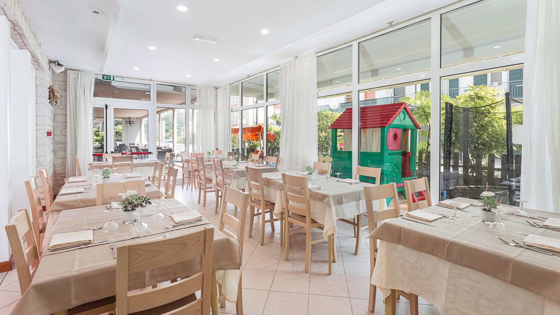 Bright dining room with set tables and children's play area.