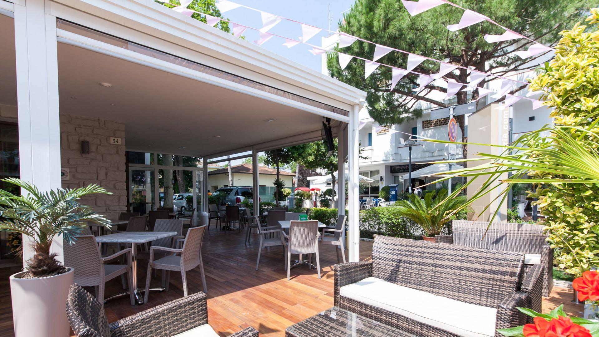 Terrazza all'aperto con mobili in rattan e decorazioni floreali.