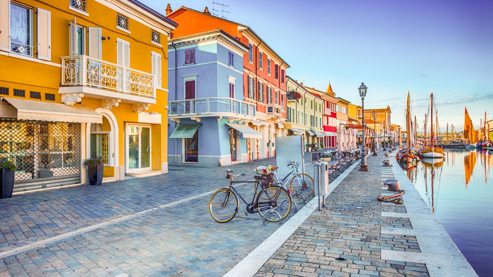 Strada con case colorate e biciclette lungo un canale.