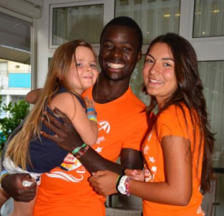 Three smiling people wearing orange shirts.