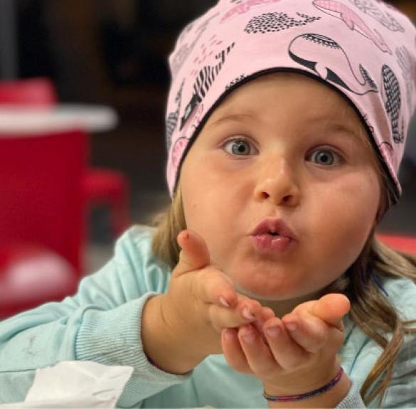 Girl in pink hat blowing a kiss.