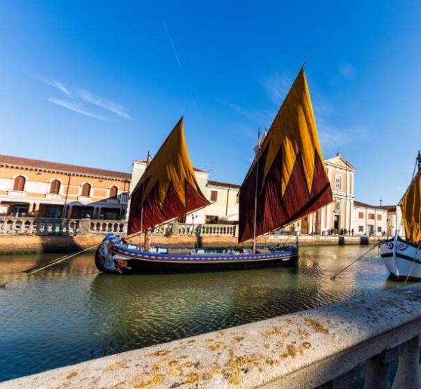 Barche a vela storiche nel canale di Cesenatico sotto un cielo limpido.