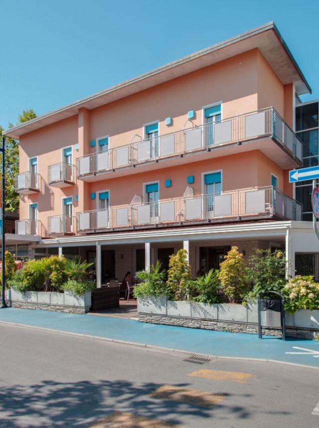 Edificio moderno a tre piani con balconi e piante.