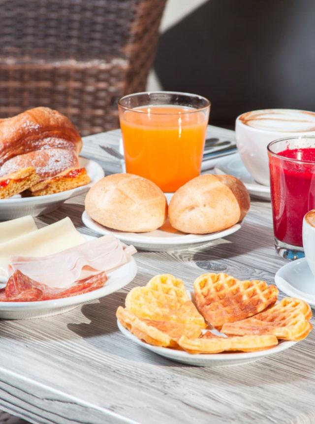 Colazione con waffle, pane, salumi e succhi di frutta.